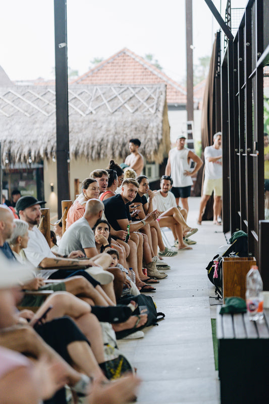 Players enjoying a padel match at a modern padel court in Canggu, Bali, surrounded by palm trees and vibrant sports club facilities.