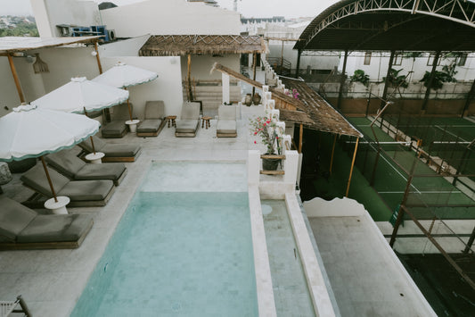 A vibrant view of Bali Social Club's wellness center in Canggu featuring padel courts, ice bath, sauna, pool, and community members enjoying post-travel recovery activities—a hub for the padel community and holistic fitness in Bali.